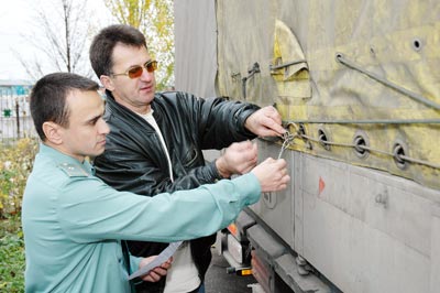 Государственный таможенный инспектор новочебоксарец Азат Алеев (слева) проверяет целостность пломбы на грузовике, уходящем за границу. Фото Валерия Бакланова. 