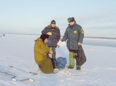 Спасатели предупреждают рыбака, сидящего у кромки льда, об опасности и предлагают ему найти другое место.  