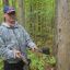 Олег Михайлов с помощью инструментов лесника показывает, как отмечаются деревья на рубку.